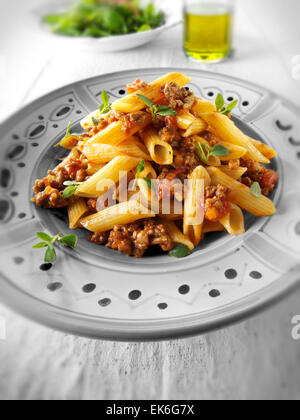 Fresh cooked pene and bolognese ragout served on a plate in a table setting. Serving suggestion Stock Photo