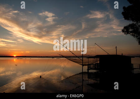 Fishing hut with a big net on a lagoon at sunset, Pialassa Baiona, Marina Romea di Ravenna, Italy Stock Photo