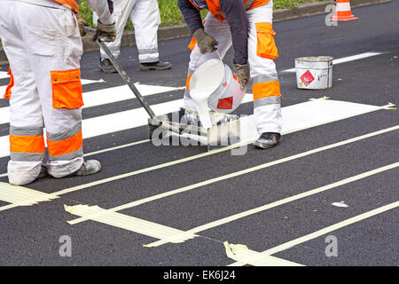 Two workers making of a new pedestrian crossing on the road Stock Photo
