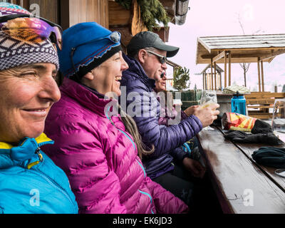 Backcountry skiers relax on exterior deck, Rifugio Fuciade, Pale di San Martino, Dolomite Mountains, Alps, Italy Stock Photo