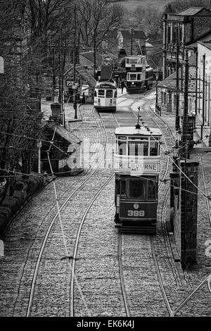 Monochrome: Tram 399 (served in Leeds in 1926) moves towards the village terminus where a driver enters Tram 345 (Leeds 1921) Stock Photo