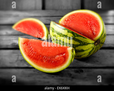 Fresh cut red watermelon, whole and sliced, on a wood background setting Stock Photo