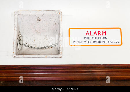 Passenger alarm chain inside an old fashioned railway carriage, and sign warning about improper use Stock Photo