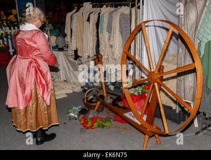 Woman (50-60 years) spinner in traditional costume using a hand driven spinning wheel to spin alpaca yarn Stock Photo