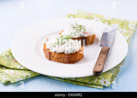 Canapes with soft cheese spread on white plate, selective focus Stock Photo