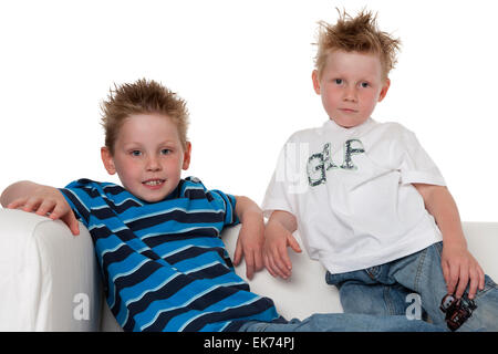 Two brothers posing while sitting on a bench on white background Stock Photo
