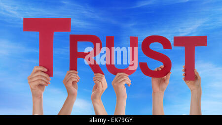 Many Caucasian People And Hands Holding Red Straight Letters Or Characters Building The English Word Trust On Blue Sky Stock Photo