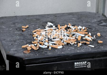 A pile of extinguished cigarette butts on top of litter bin Stock Photo
