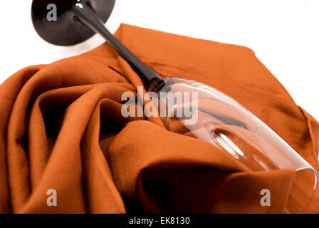 Tall wine glass lying on table, on fabrics in pleat,on white background Stock Photo