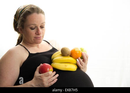 pregnant woman eating fruit isolated on white background Stock Photo