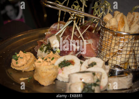 Assorted canapés on a plate including cheese straws, chicken stuffed with spinach and olives wrapped in bacon in a VIP area. Stock Photo
