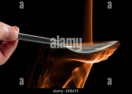 Smoke made to look like fire pouring on a spoon over a black background. Stock Photo
