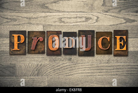 The word 'PRODUCE' theme written in vintage, ink stained, wooden letterpress type on a wood grained background. Stock Photo