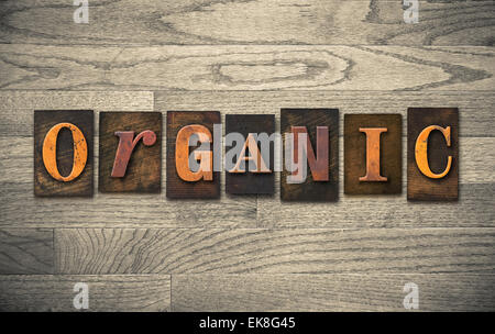 The word "ORGANIC" theme written in vintage, ink stained, wooden letterpress type on a wood grained background. Stock Photo