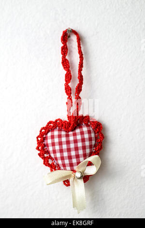 handmade knitted heart shape hanging on the white wall Stock Photo