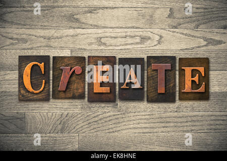 The word "CREATE" theme written in vintage, ink stained, wooden letterpress type on a wood grained background. Stock Photo
