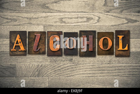 The word 'ALCOHOL' theme written in vintage, ink stained, wooden letterpress type on a wood grained background. Stock Photo