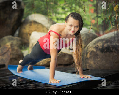 Woman is practicing yoga outdoor. Plank pose. Stock Photo