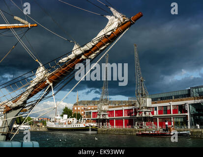 The prow of a tall ship on Bristol's Harbourside with the MShed museum and its cranes and boats in the background. Stock Photo