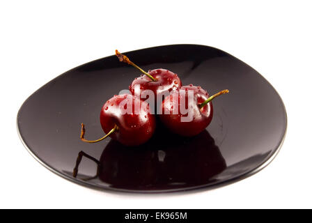 cherries on a black saucer isolated on white Stock Photo