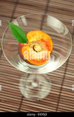 peach in the martini glass on a bamboo mat Stock Photo