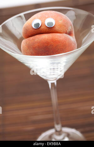 Peach with eyes in the glass martini on a bamboo mat Stock Photo