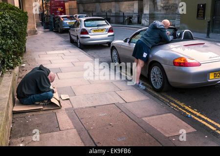 Bath, Somerset, UK. 8th April, 2015. Divided society economically as one man begs and another fills his Porsche Boxster with shopping. Credit:  Richard Wayman/Alamy Live News Stock Photo