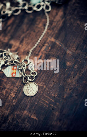 St christopher on a charm bracelet on textured wood background with an applied vintage filter Stock Photo