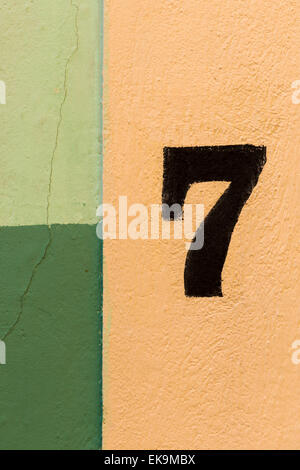 The number seven painted on a coulourful wall of yellow and green patches Stock Photo