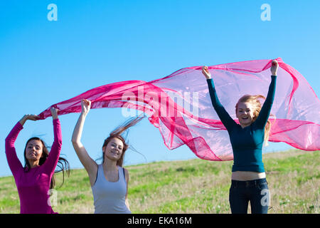 three young beautiful woman jumping with tissue into the field a Stock Photo