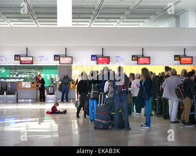 Lines of charter flight passengers and luggage wait at airport terminal to check in to their flight Stock Photo