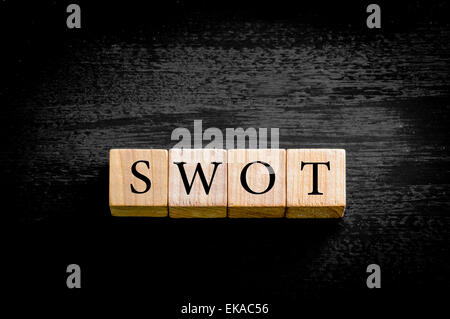 Word SWOT. Wooden small cubes with letters isolated on black background with copy space available. Concept image. Stock Photo