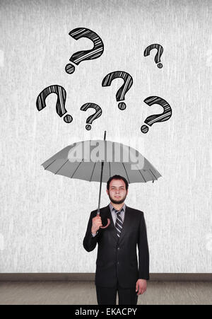 young businessman holding umbrella and falling question mark Stock Photo