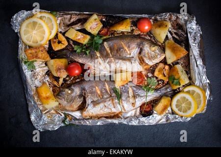 Prepared and grilled gilthead fish with vegetables and potatoes from above Stock Photo