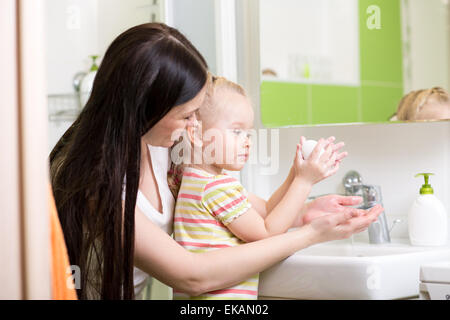 mother teaches kid washing hands in bathroom Stock Photo