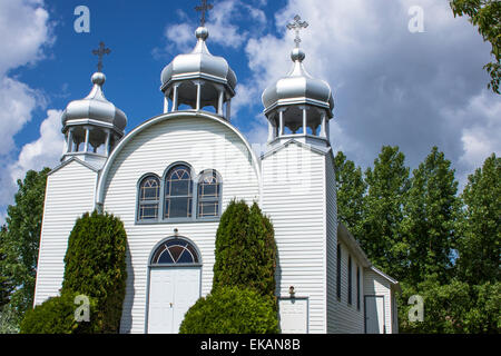 Small white country church with stained glass window and three crosses and steeples. Stock Photo