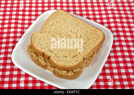 Peanut butter sandwich on whole wheat bread on a square white plate. Stock Photo
