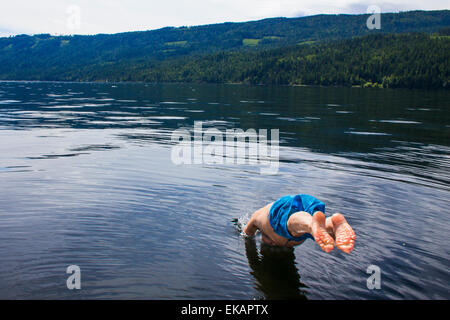 Man diving in to the deep blue waters of the lake. Stock Photo