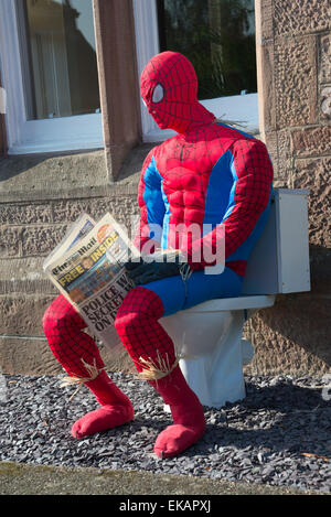 Spiderman scarecrow at scarecrow festival. Sitting on toilet reading newspaper. Stock Photo