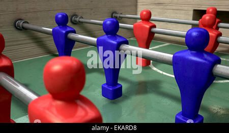 One half of a foosball table at ground level with a soccer ball in front of the red team ready to kick off a soccer match Stock Photo