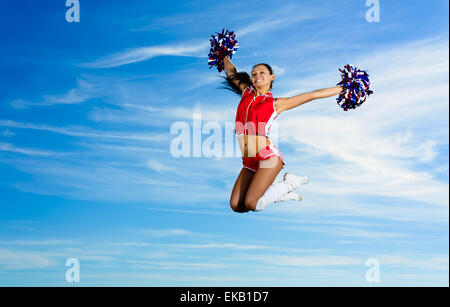 Young cheerleader in red costume jumping Stock Photo