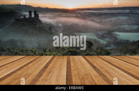 Vibrant sunrise over medieval castle ruins with fog in rural landscape with wooden planks floor Stock Photo