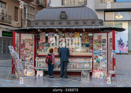 People stand at a red newspaper and magazine kiosk with fancy roof, Cartagena, Murcia Region, Spain, Europe Stock Photo