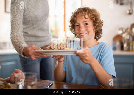 Mother serving spaghetti to children at dining table Stock Photo