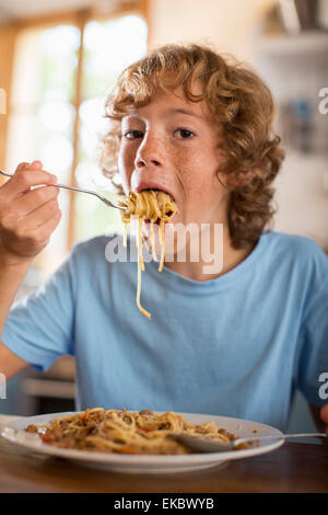 Teenage boy eating spaghetti at dining table Stock Photo