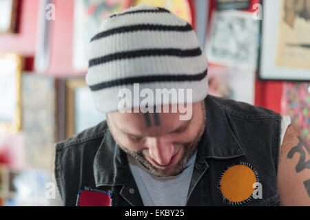 Close up of male punk shop keeper smiling and looking down in vintage toy shop Stock Photo
