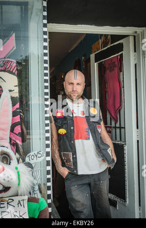 Portrait of male punk shop keeper leaning against vintage toy shop doorway Stock Photo