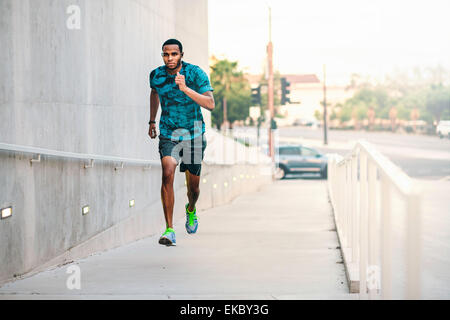 Young man running up city footbridge Stock Photo