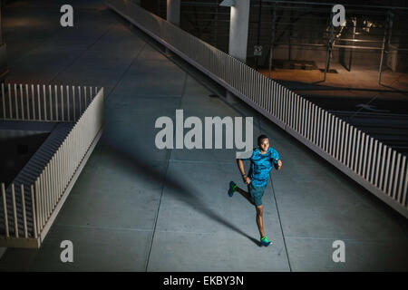 High angle view of young man running on city walkway at night Stock Photo