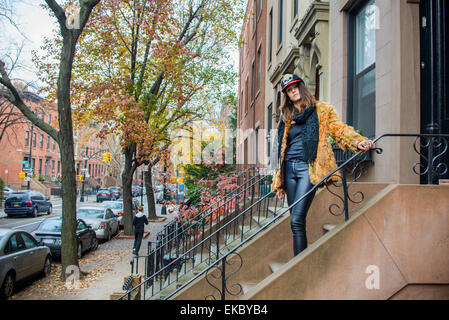 Portrait of stylish young woman posing on steps outside house Stock Photo